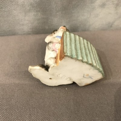 Petit chien en porcelaine au bras armé d’époque 19ème